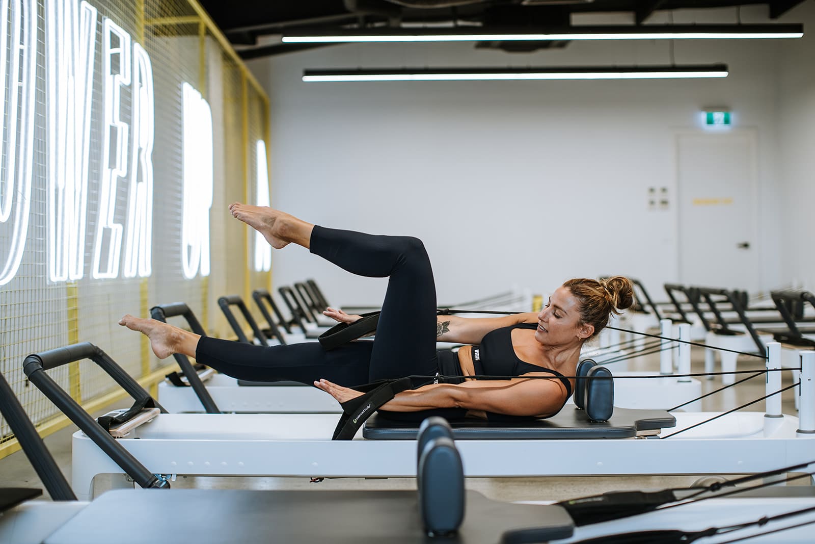Madi Browne works out on reformer bed at Upstate Studios in chic industrial space in Fitzroy.