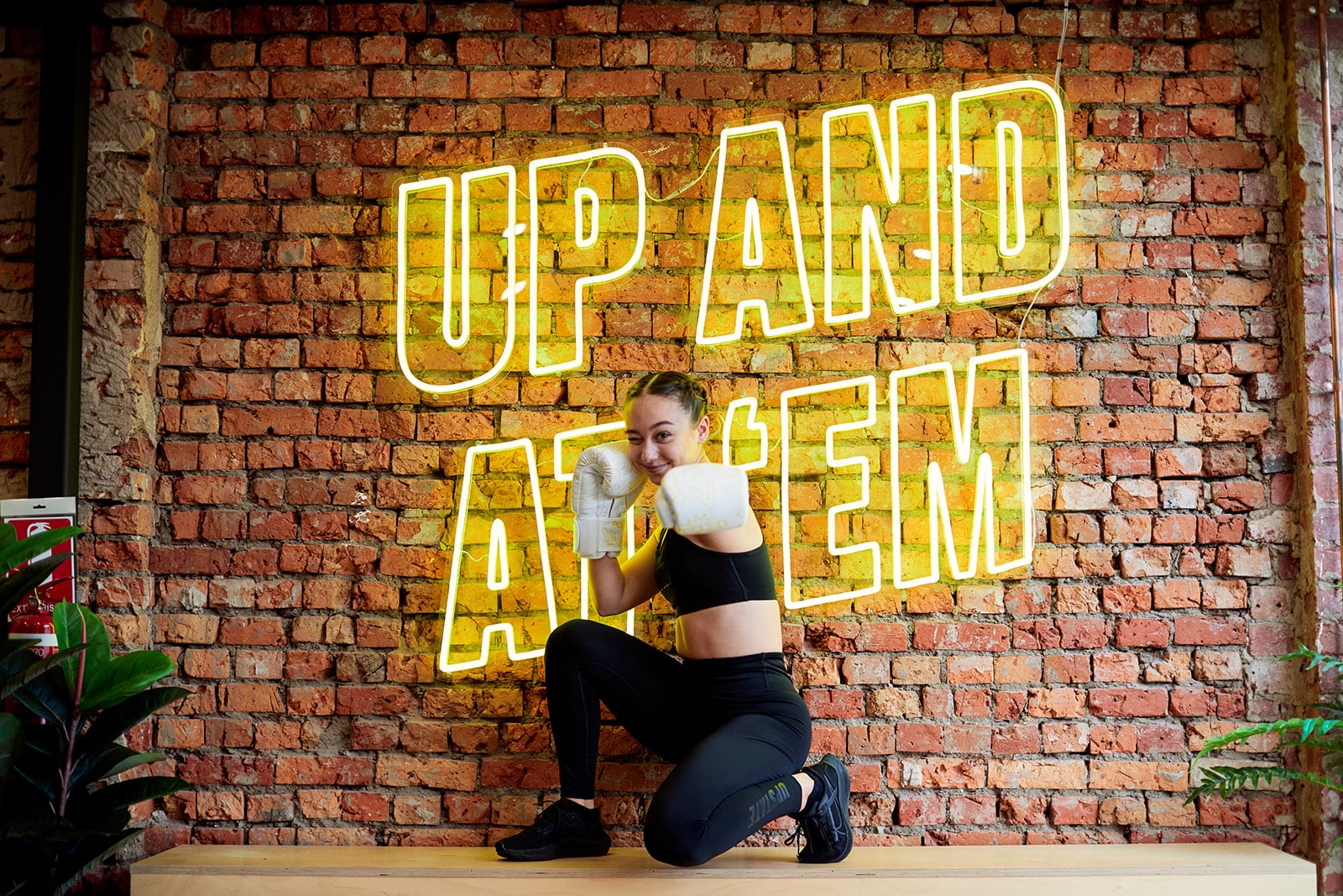 Woman who is an Upstate Instructor smiles happily as she punches towards the camera, while wearing boxing gloves.