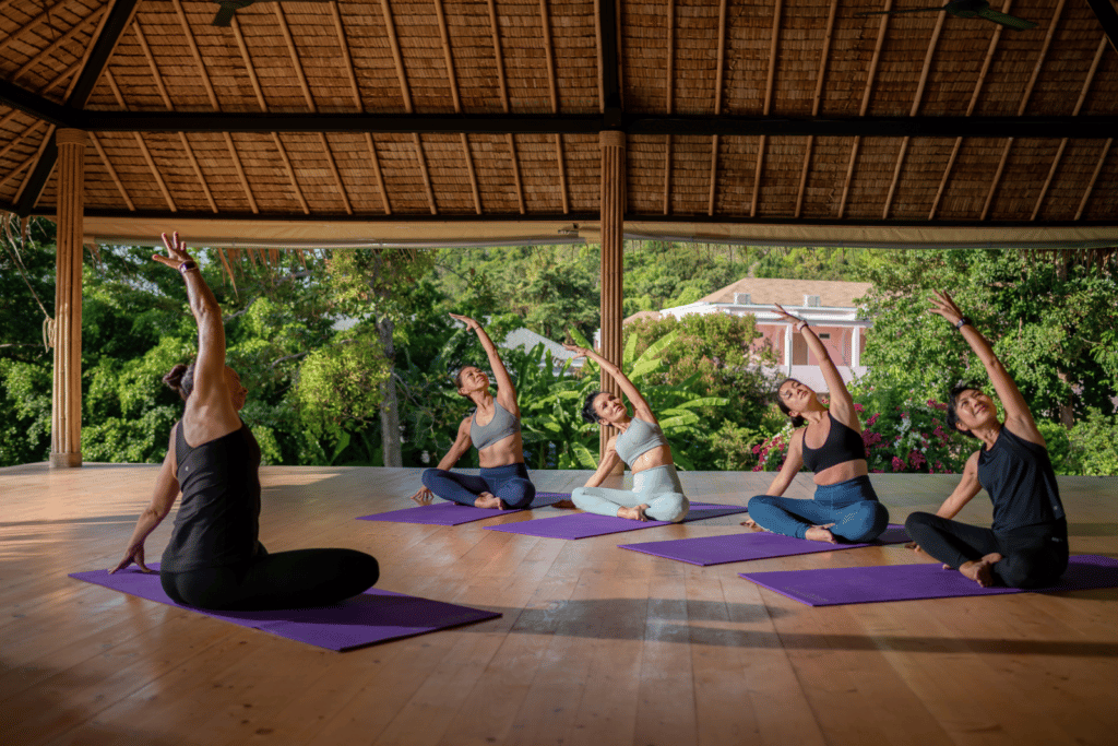 A group of people enjoy yoga in an open air shala in Thailand on the Upstate Studios retreat.