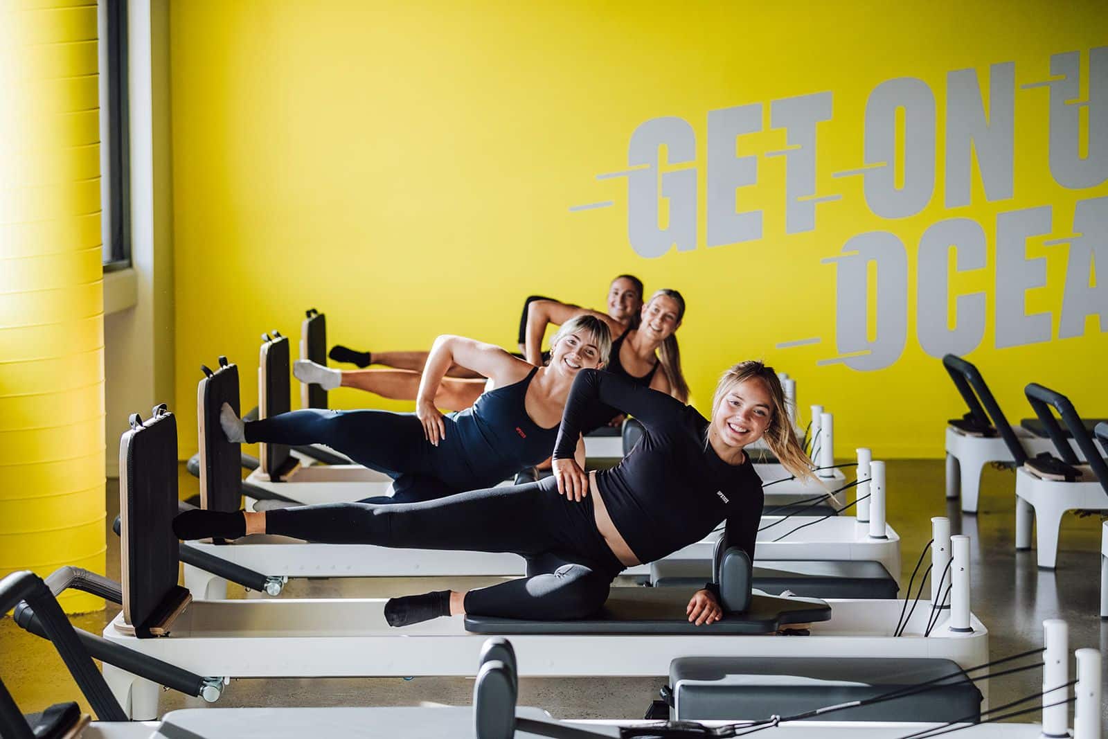 Upstaters lie back in a powerful posture on reformer pilates bed at Upstate Studios.