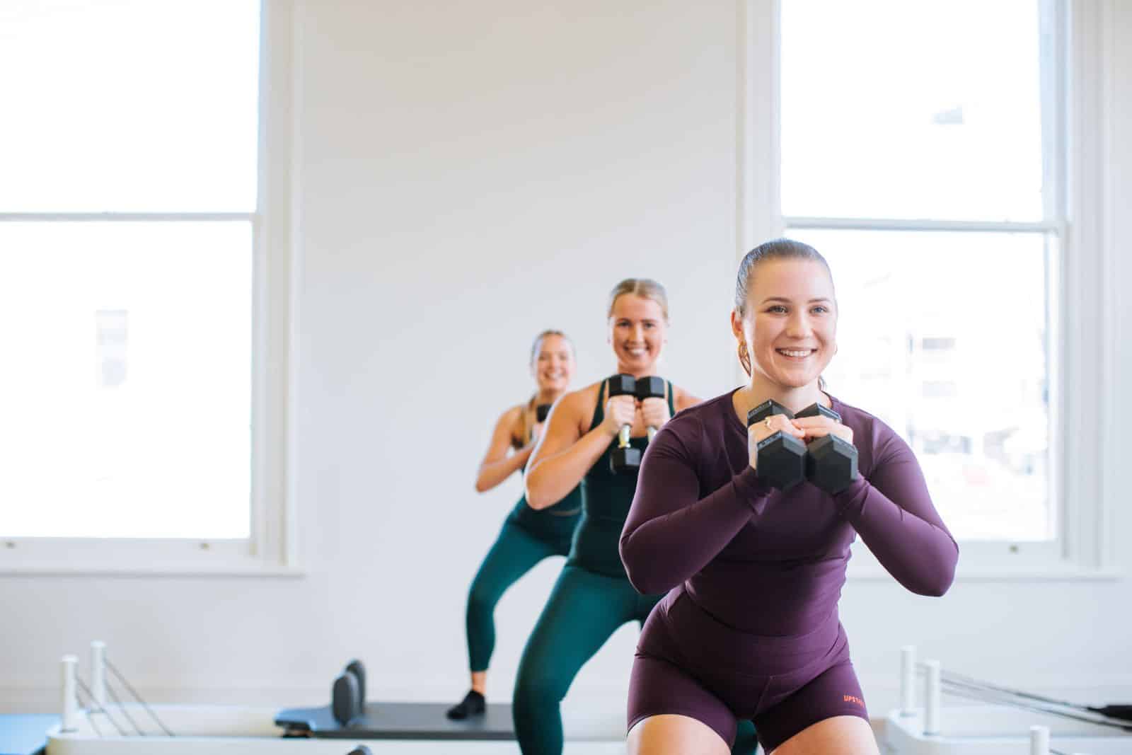 members in a reformer class in Ballarat reformer studio holding weights